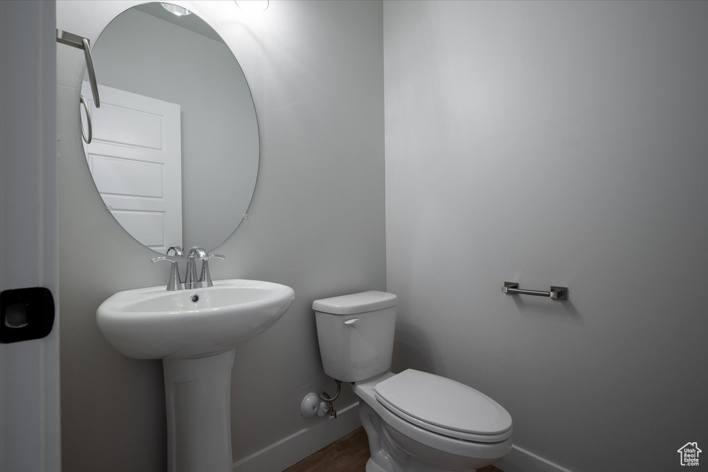Half bath featuring baseboards, toilet, and wood finished floors