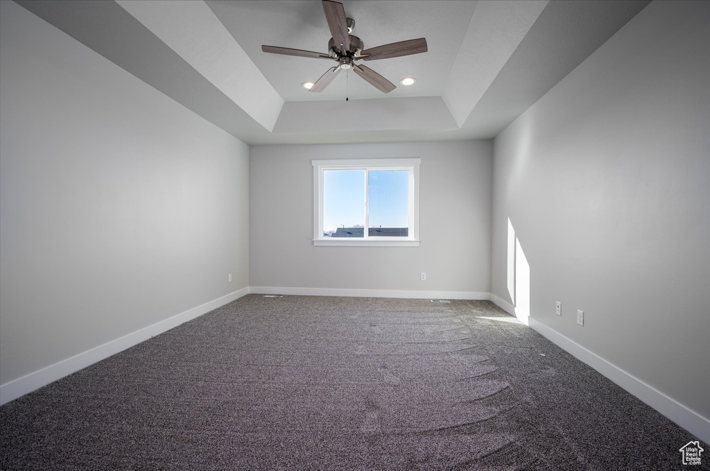 Unfurnished room featuring a tray ceiling, a ceiling fan, carpet, baseboards, and recessed lighting