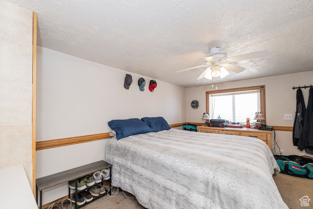 Bedroom with light carpet, a textured ceiling, and a ceiling fan
