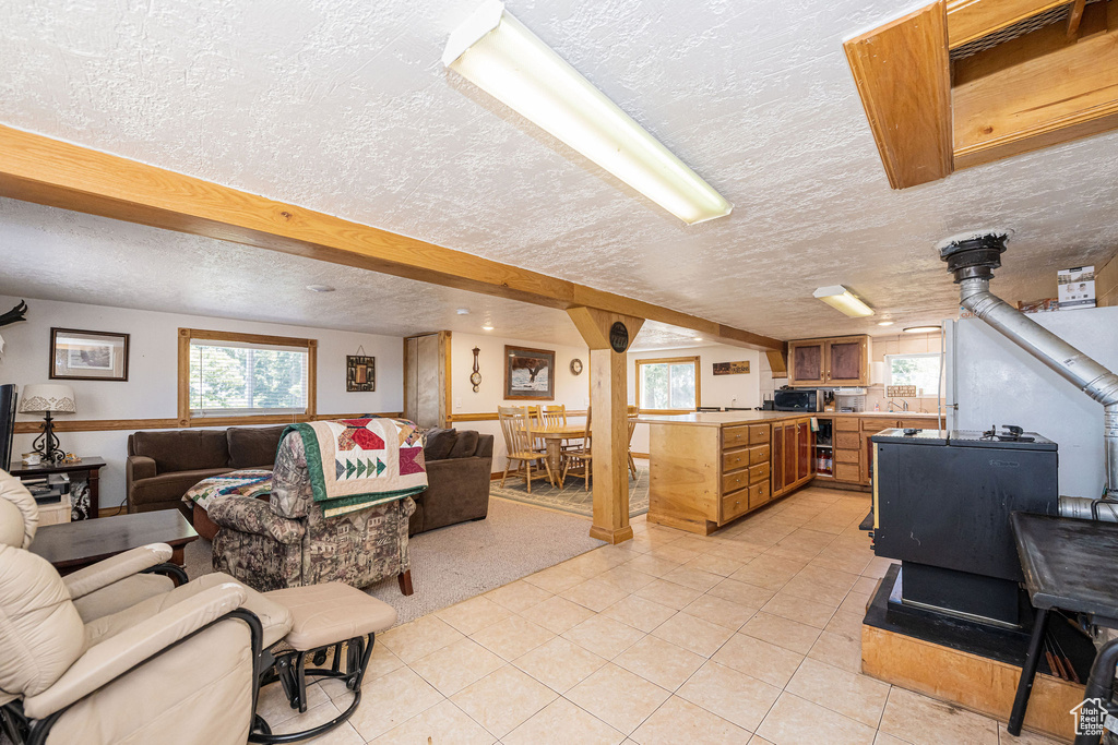 Living area with a wood stove, a textured ceiling, and light tile patterned floors