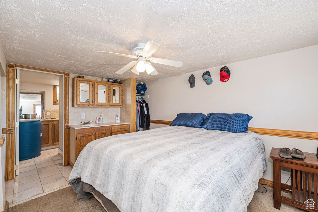 Bedroom featuring a textured ceiling, wet bar, a ceiling fan, a closet, and ensuite bathroom