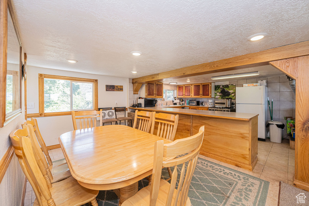 Dining space with a textured ceiling, recessed lighting, and light tile patterned floors