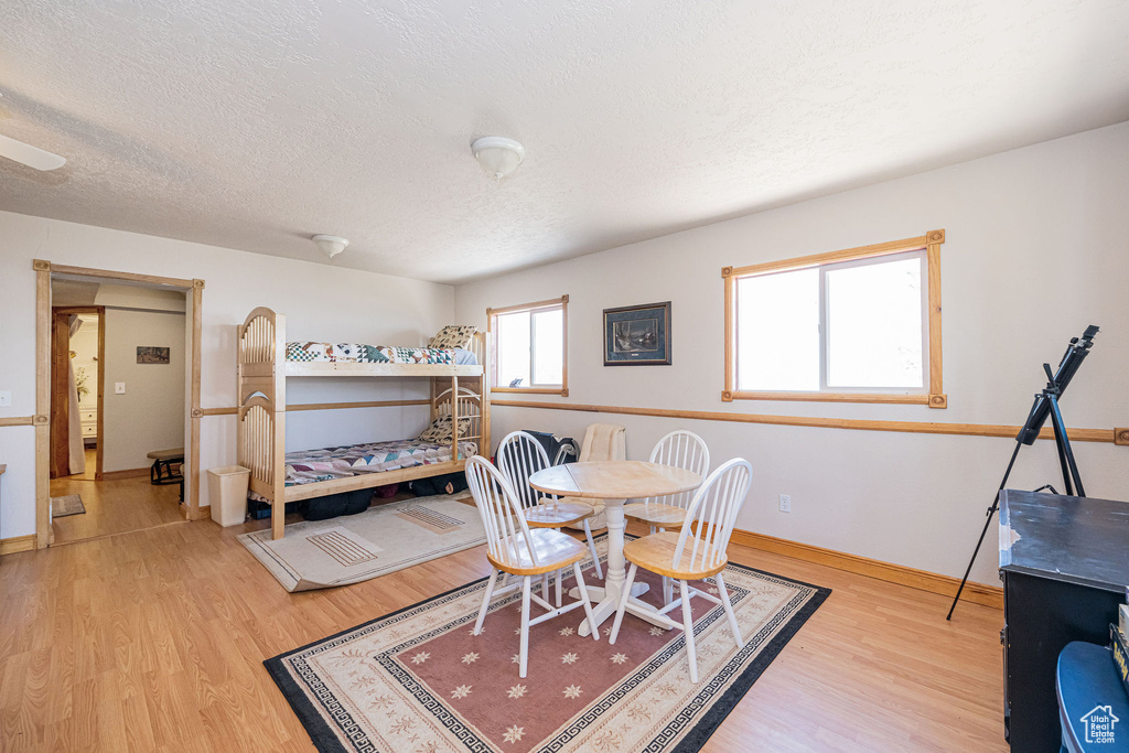 Dining area featuring light wood finished floors, a textured ceiling, and baseboards