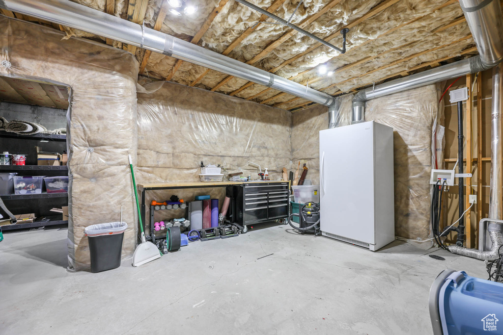 Unfinished below grade area featuring freestanding refrigerator