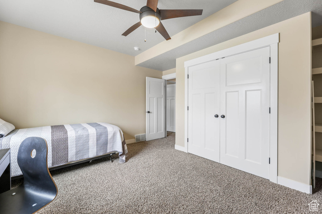Carpeted bedroom featuring baseboards, a closet, and ceiling fan