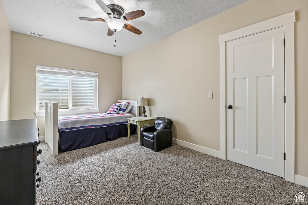 Carpeted bedroom featuring baseboards, a textured ceiling, and a ceiling fan