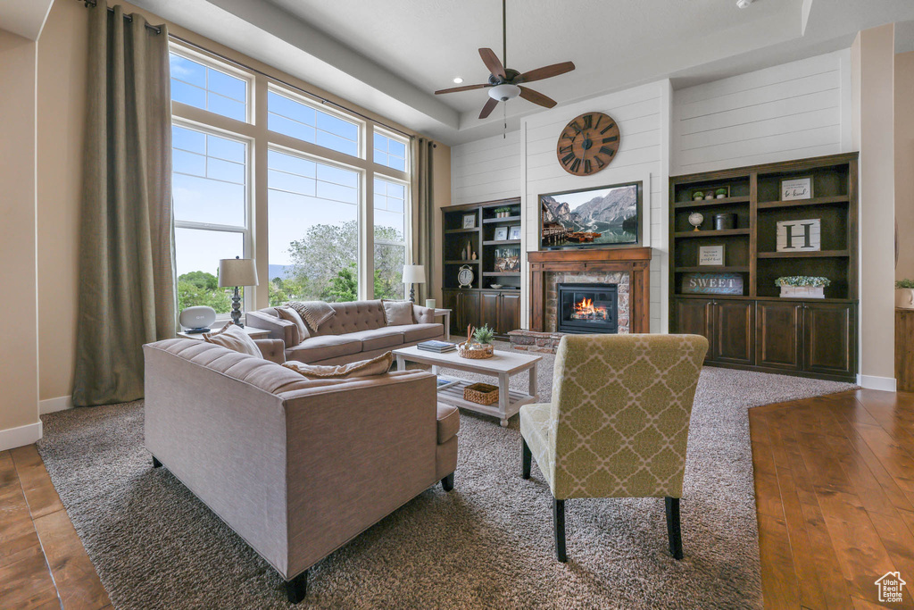 Living room featuring ceiling fan, a brick fireplace, wood walls, recessed lighting, and baseboards