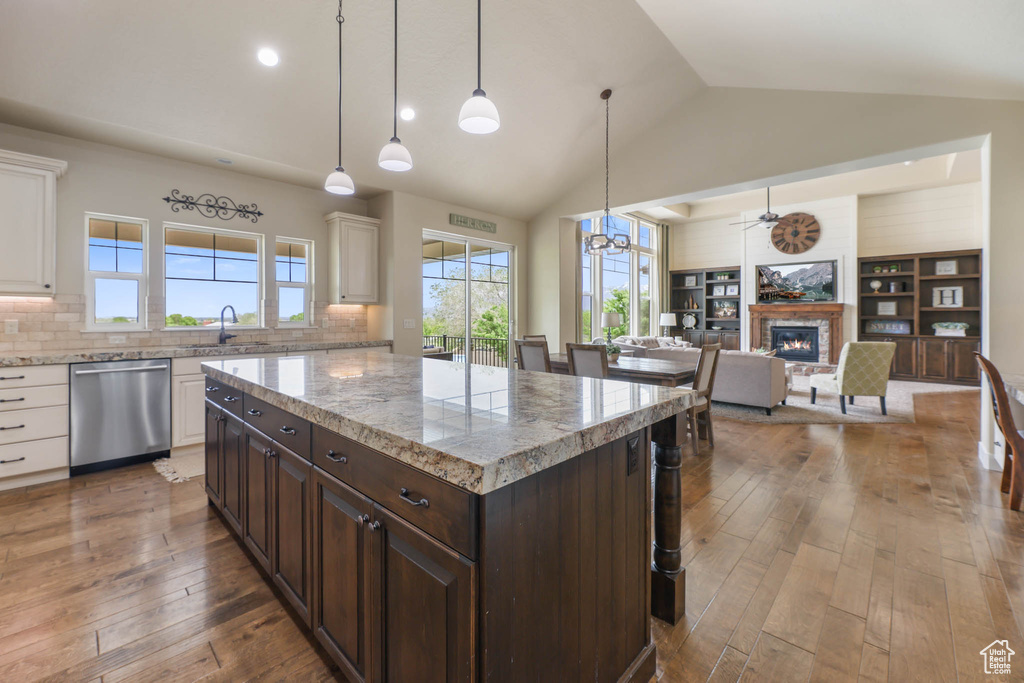 Kitchen featuring dishwasher, a sink, white cabinetry, wood-type flooring, and lofted ceiling