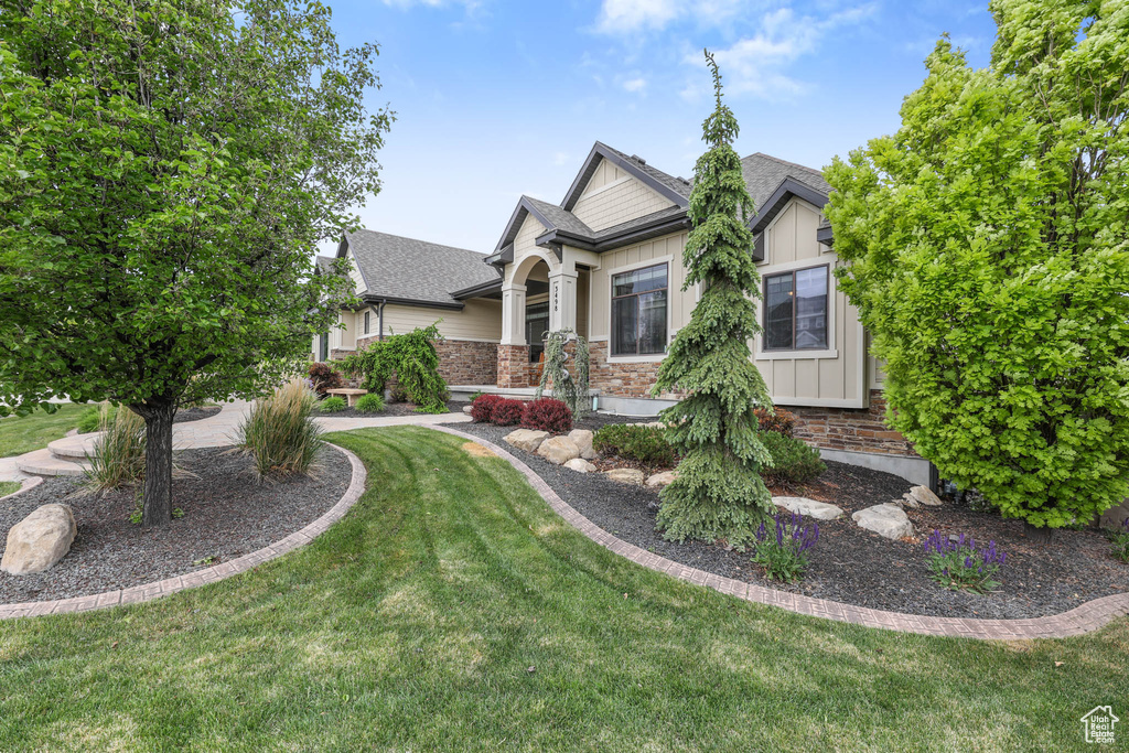 Craftsman-style home featuring board and batten siding, a front lawn, and roof with shingles