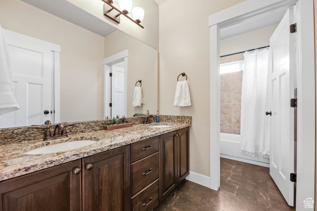 Bathroom featuring double vanity, baseboards, and shower / bath combo