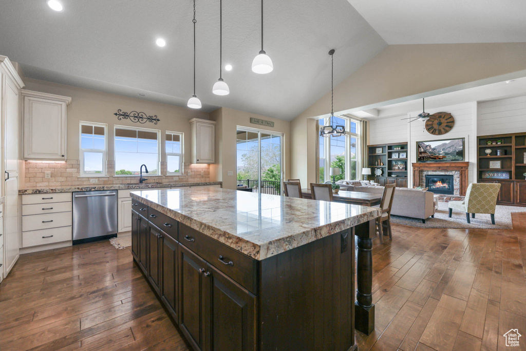 Kitchen with stainless steel dishwasher, vaulted ceiling, white cabinetry, a glass covered fireplace, and dark wood finished floors
