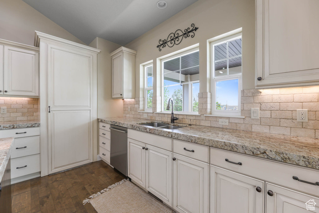 Kitchen with a sink, stainless steel dishwasher, tasteful backsplash, dark wood-type flooring, and white cabinetry