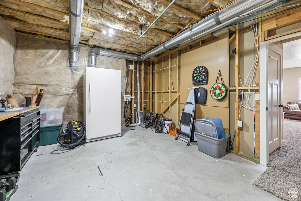 Unfinished basement with freestanding refrigerator