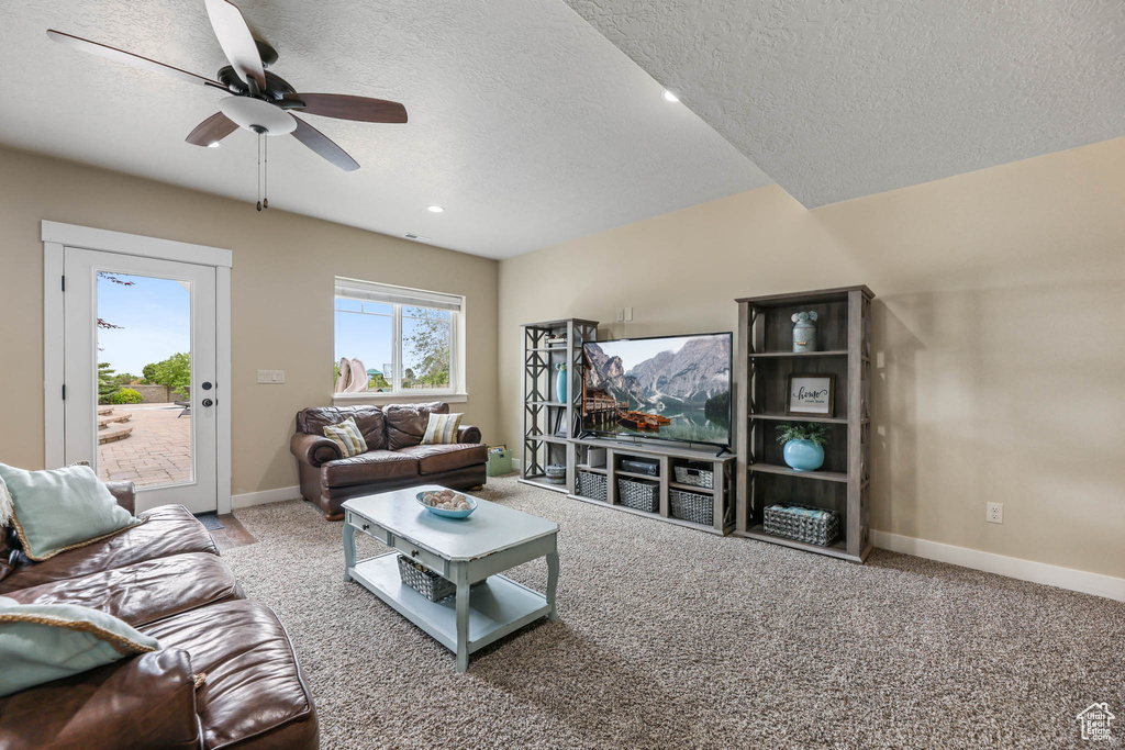 Carpeted living area featuring a ceiling fan, a textured ceiling, baseboards, and recessed lighting