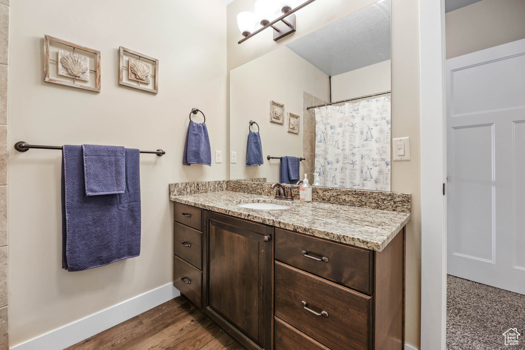 Full bath with baseboards, vanity, wood finished floors, and curtained shower