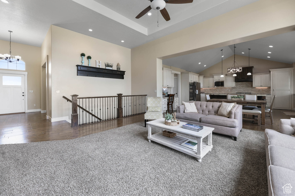 Living area featuring a chandelier, dark wood-style floors, a ceiling fan, recessed lighting, and high vaulted ceiling