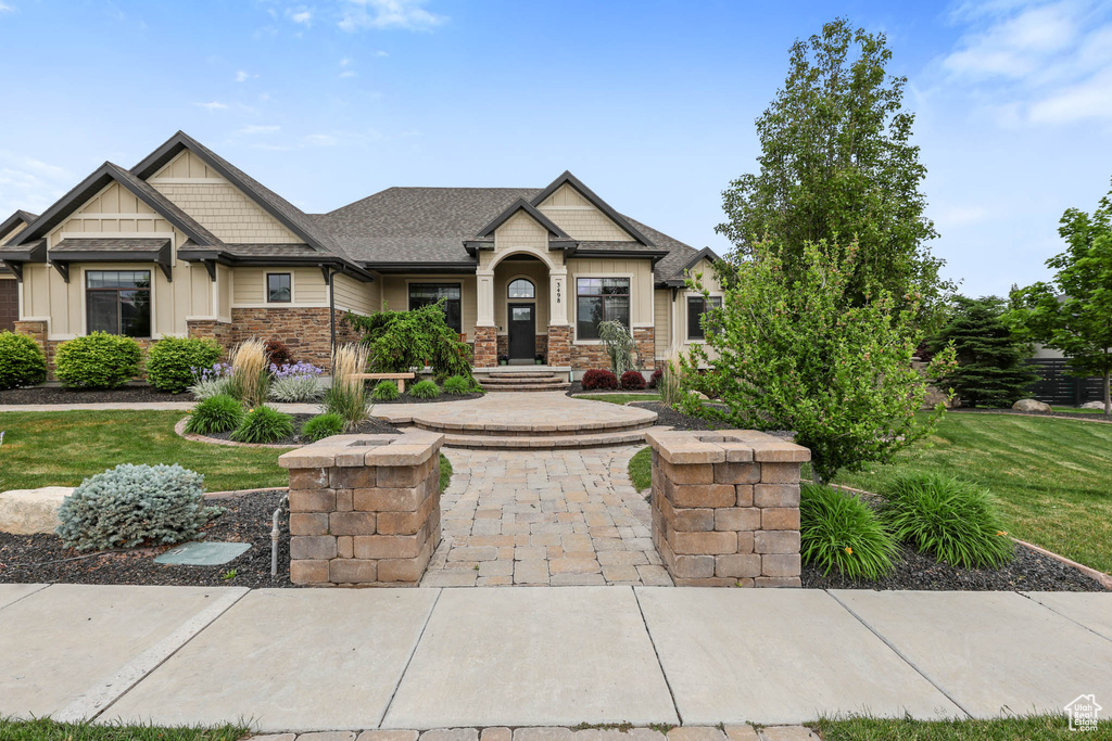Craftsman-style home with a front lawn, stone siding, and board and batten siding