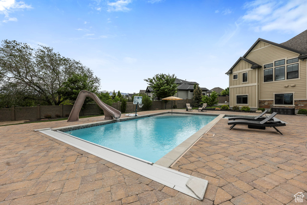 View of pool with a water slide, a patio area, and a fenced backyard