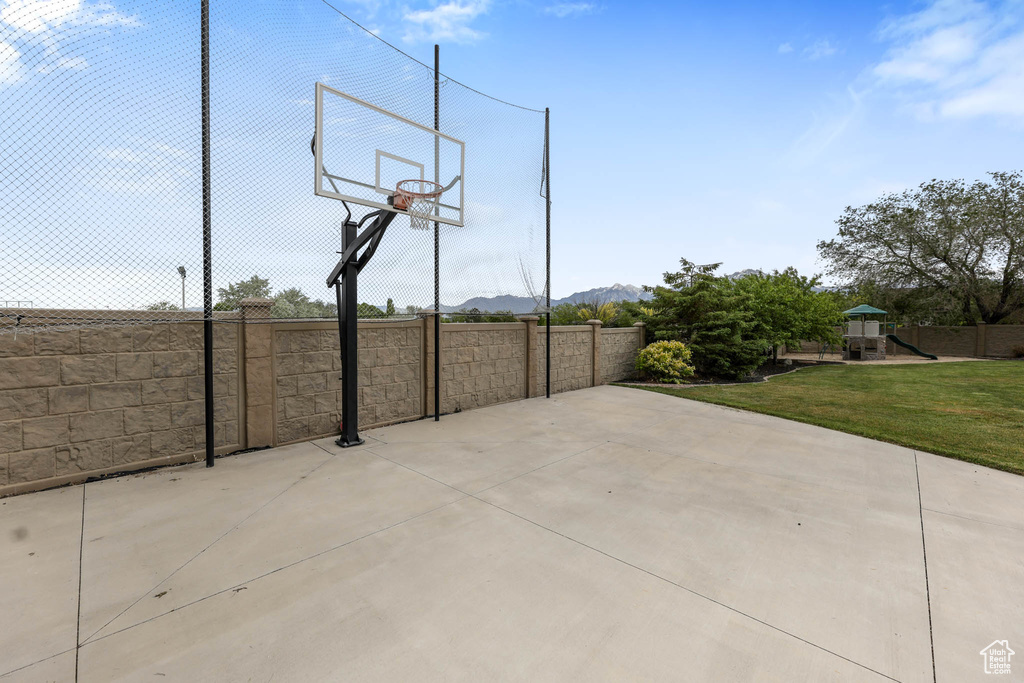 View of basketball court with a playground, a mountain view, and basketball hoop