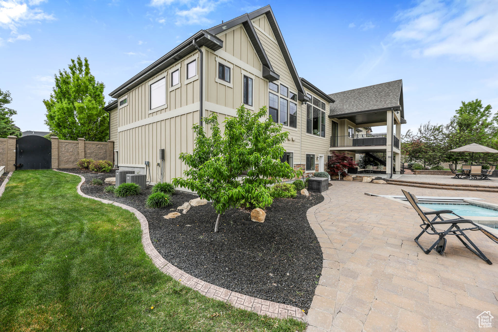 Back of property featuring board and batten siding, a patio, a balcony, a gate, and an outdoor pool