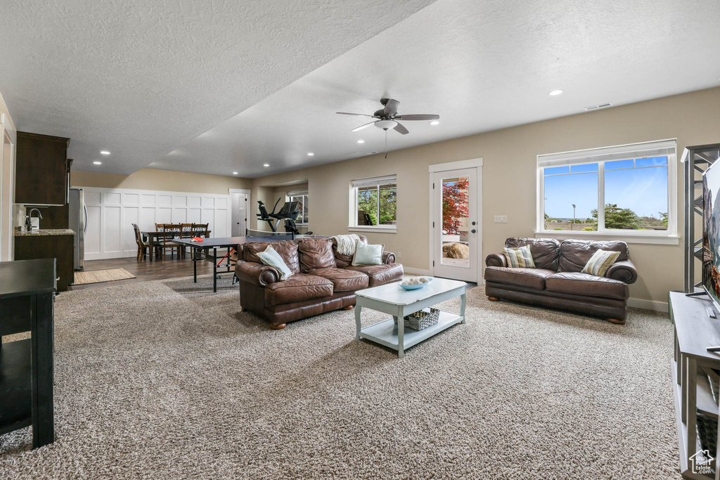 Living area with carpet flooring, a ceiling fan, recessed lighting, a textured ceiling, and baseboards
