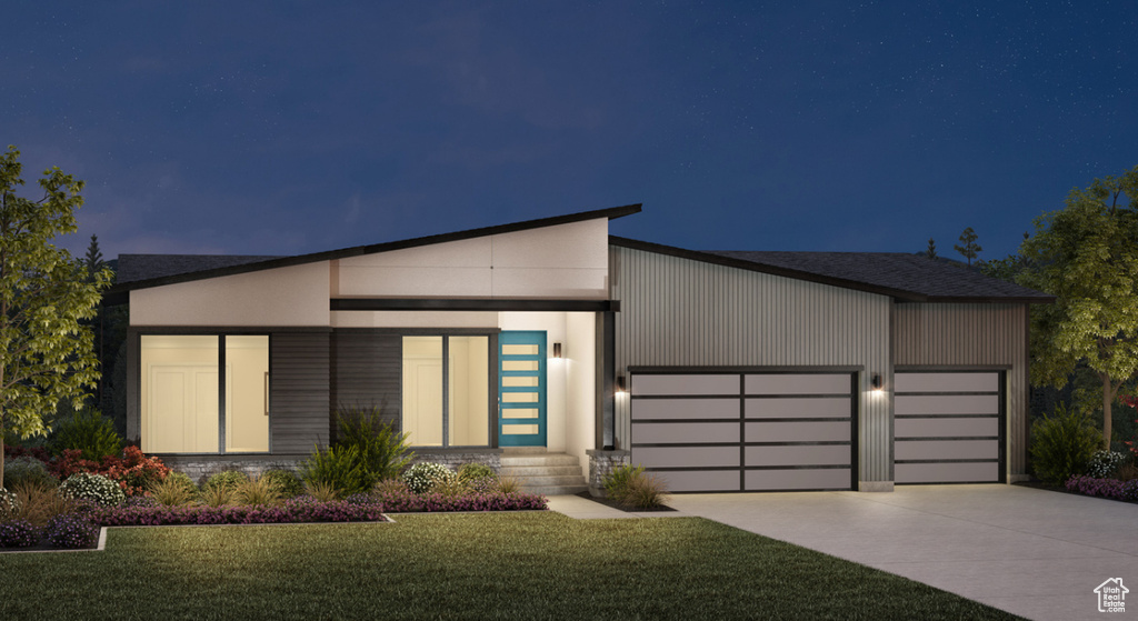 Modern home featuring driveway, a garage, and a yard