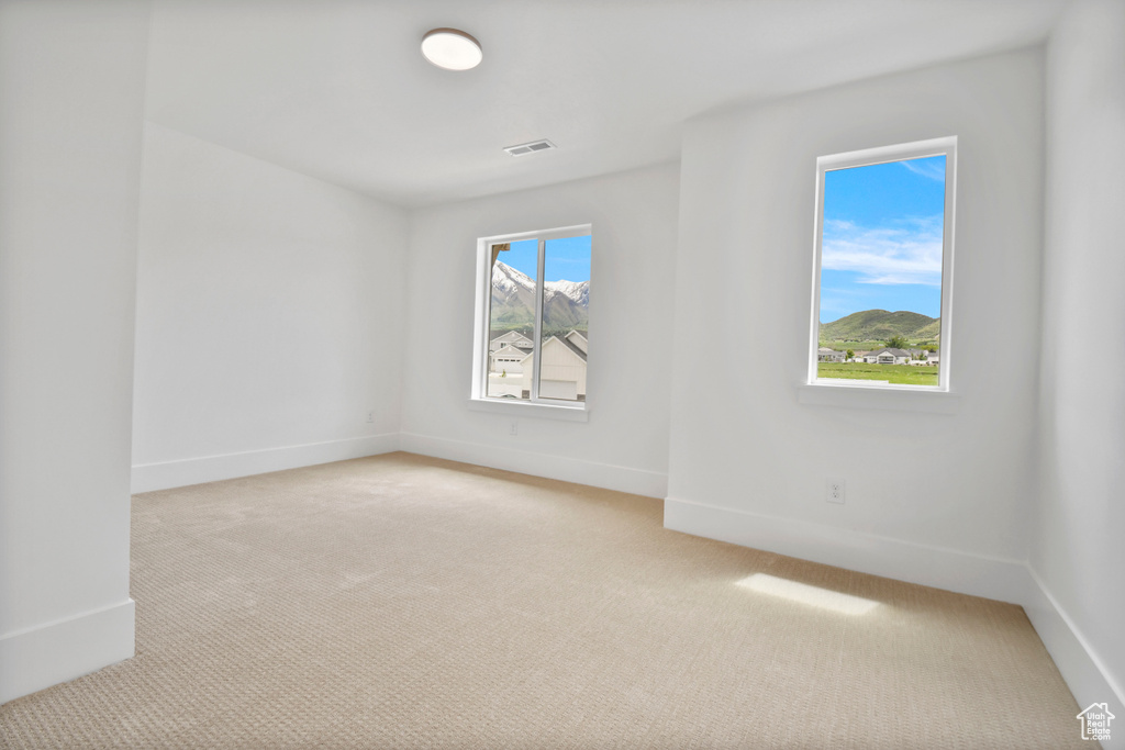 Unfurnished room featuring light carpet and baseboards