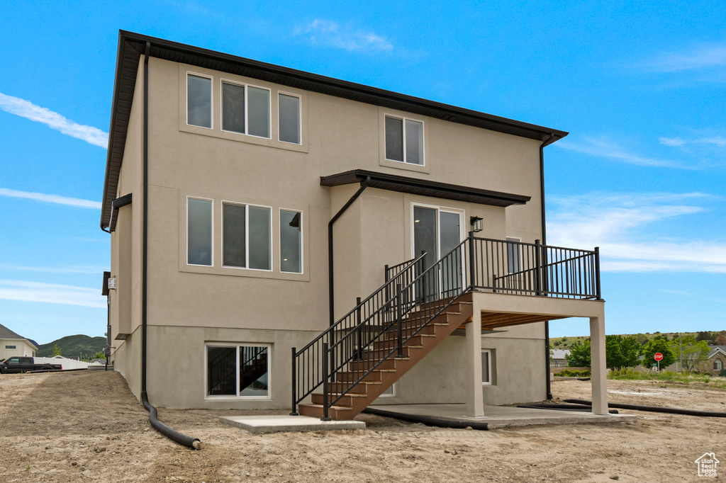 Back of house with stucco siding, a patio area, stairs, and a wooden deck