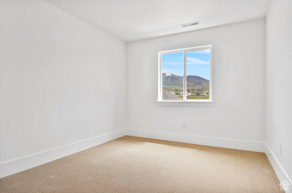 Empty room with light colored carpet, baseboards, and a mountain view
