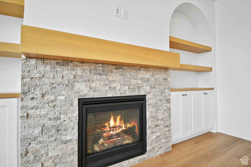 Detailed view of wood finished floors, a glass covered fireplace, and baseboards