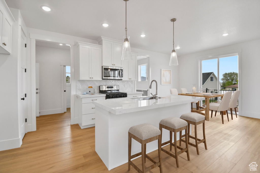 Kitchen featuring appliances with stainless steel finishes, a sink, plenty of natural light, light wood finished floors, and recessed lighting
