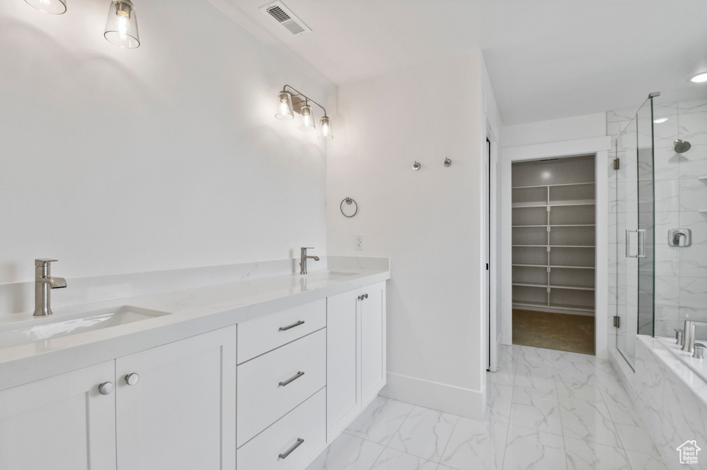 Full bath featuring a marble finish shower, marble look tile flooring, a walk in closet, baseboards, and double vanity