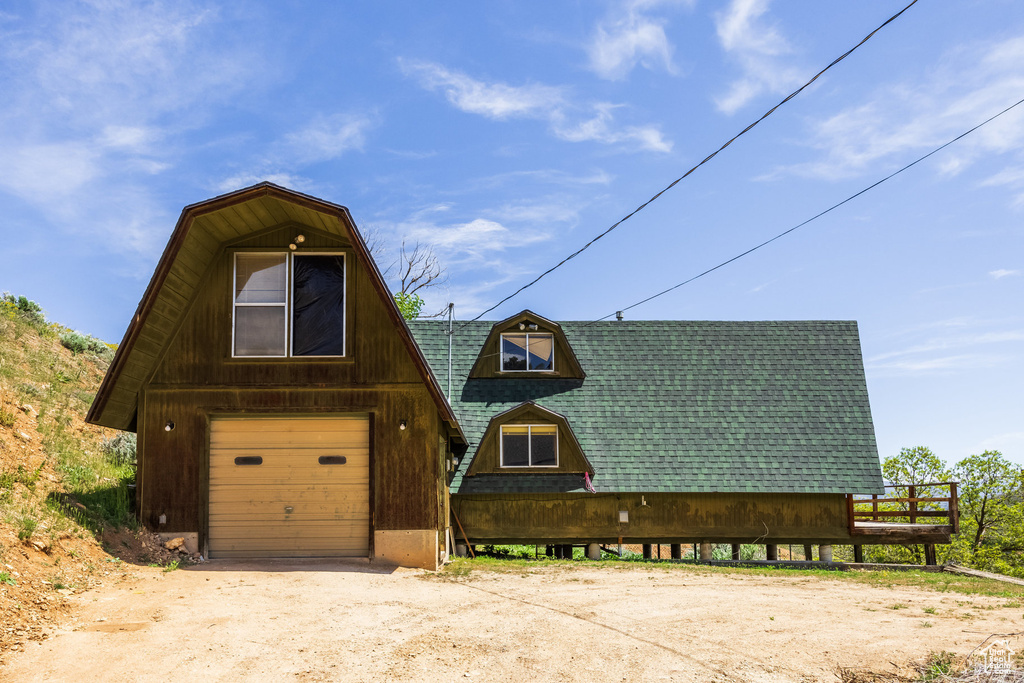 A-frame style home featuring roof with shingles, driveway, and a garage