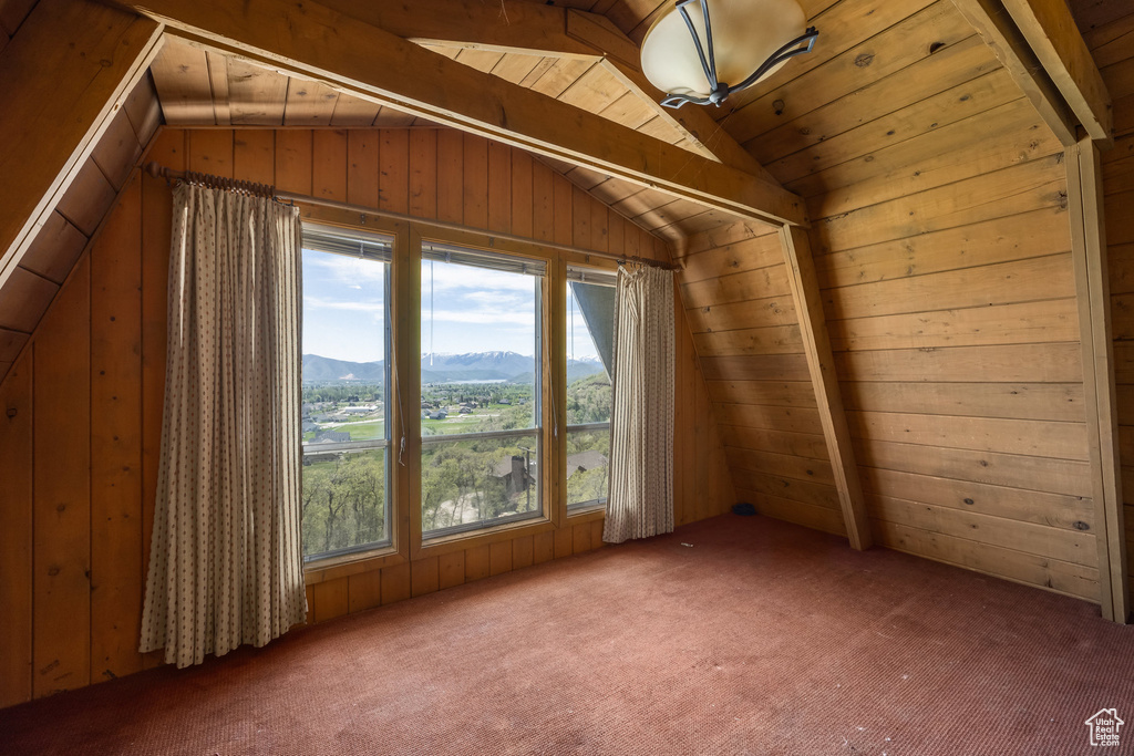 Bonus room with vaulted ceiling, carpet flooring, a mountain view, and wood walls