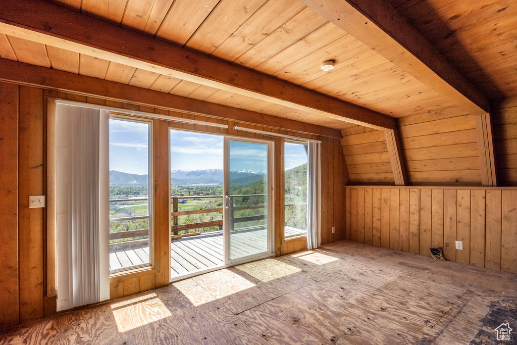 Empty room featuring a mountain view and wooden ceiling with exposed beams