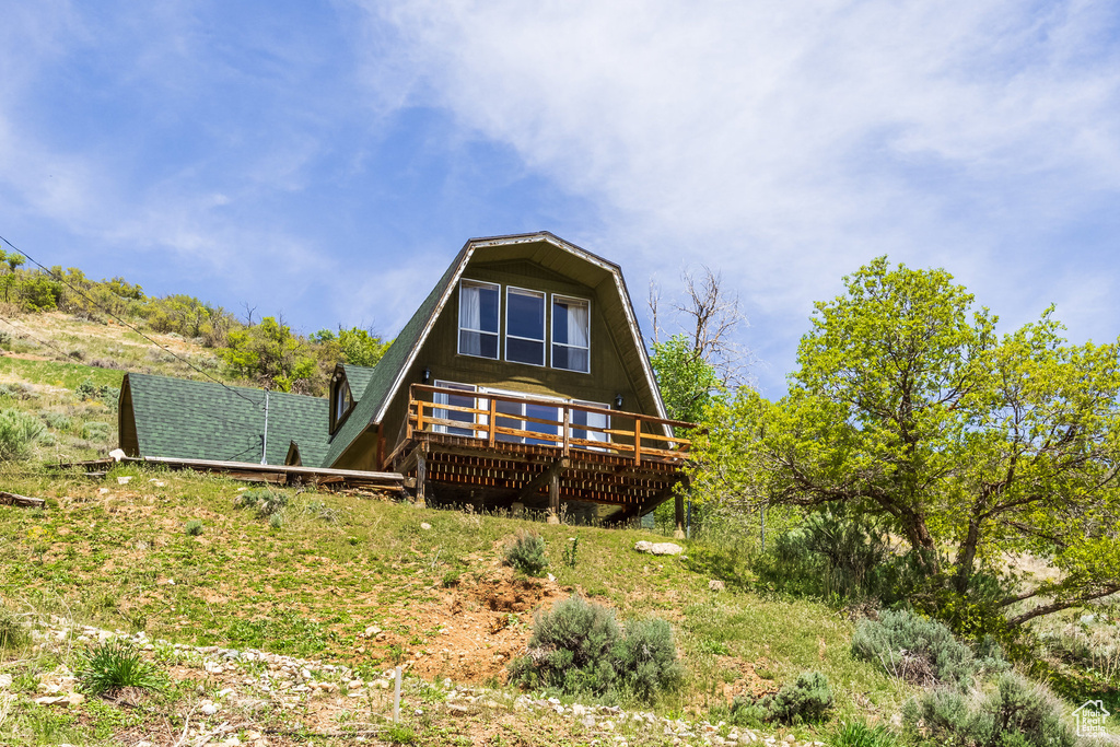 Rear view of property with a deck and a shingled roof