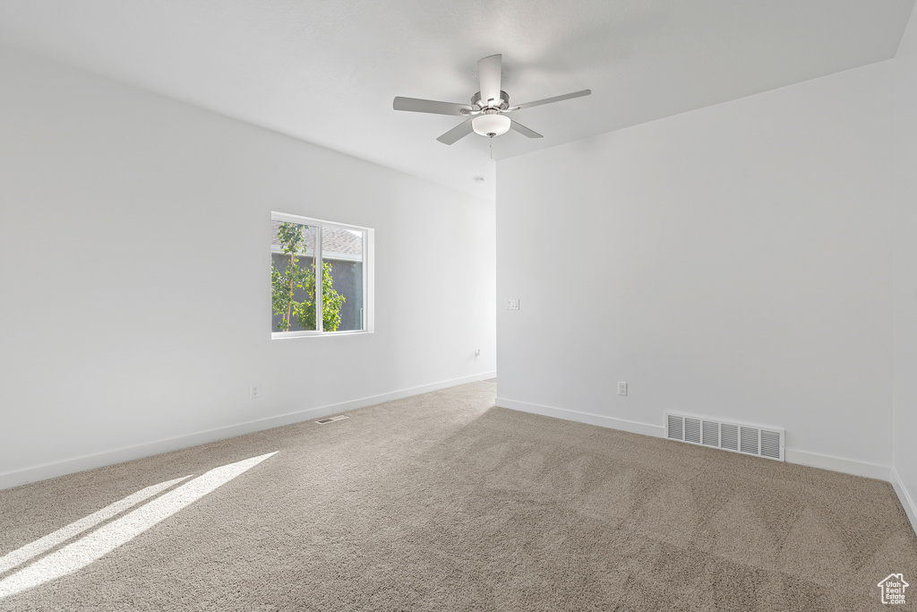Carpeted spare room with ceiling fan and baseboards