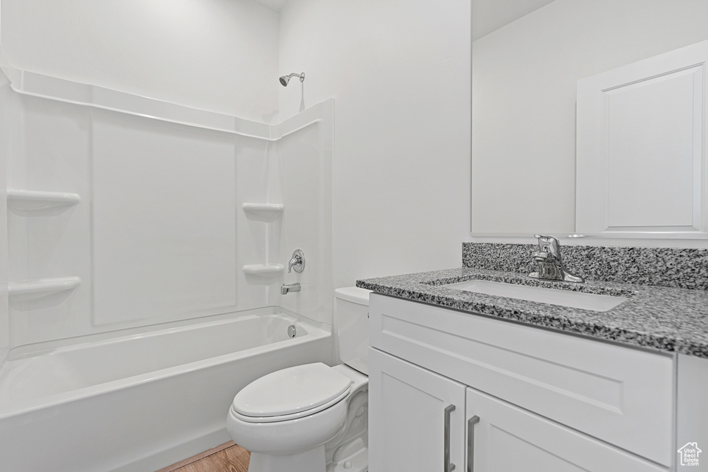 Full bathroom with toilet, wood finished floors, tub / shower combination, and vanity