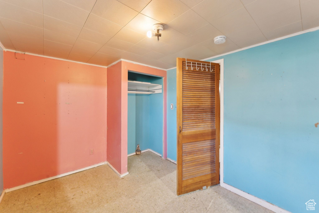 Unfurnished bedroom featuring baseboards, crown molding, and a closet