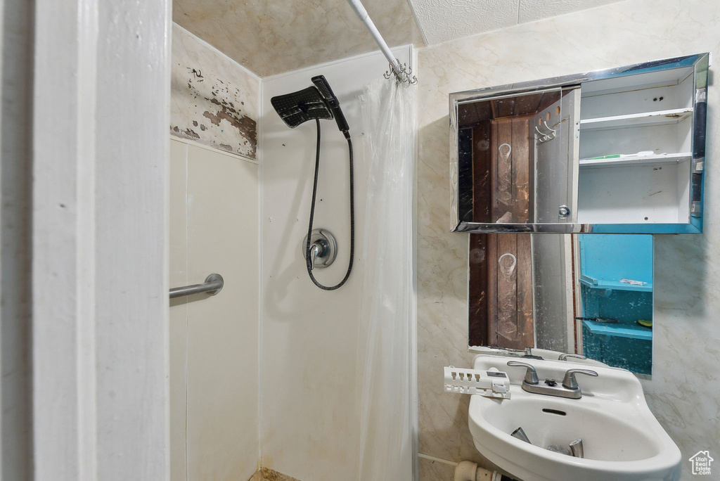Full bathroom featuring a stall shower and a sink