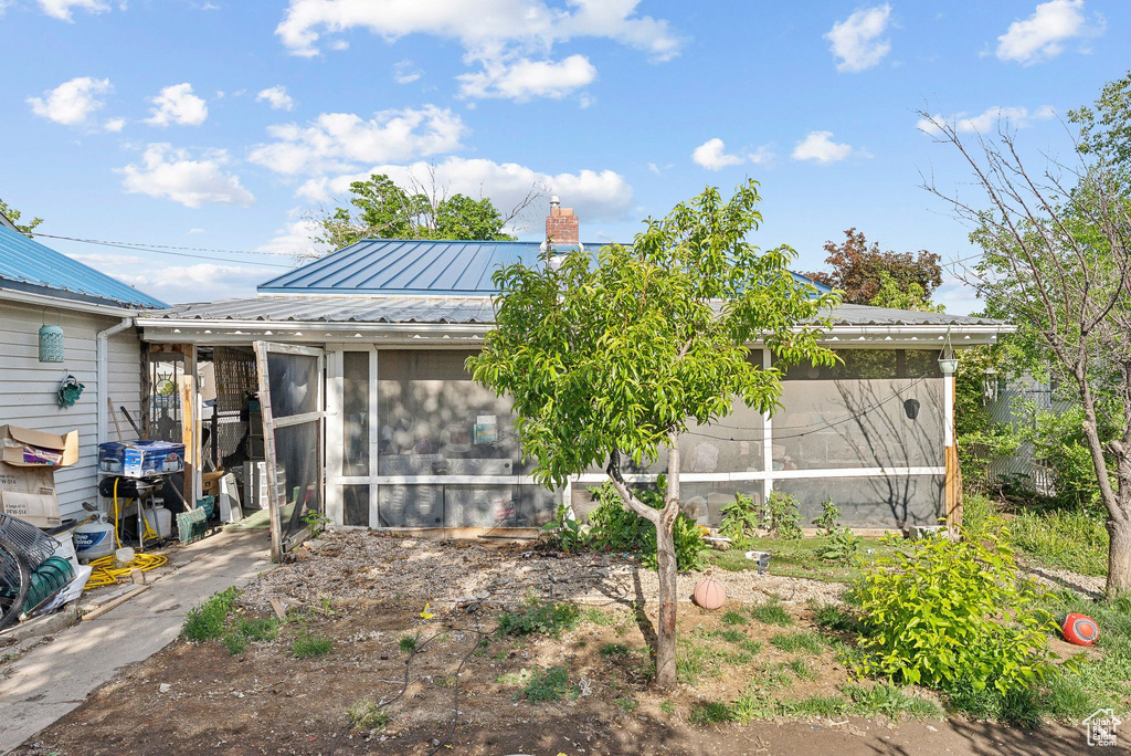 Back of property with a sunroom, metal roof, and a chimney