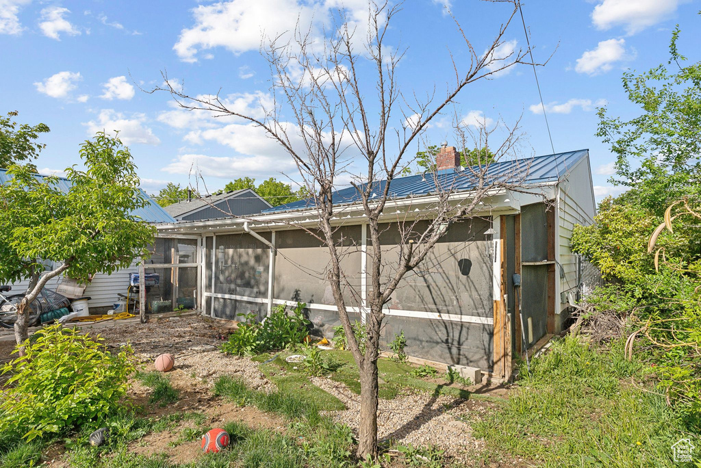 Back of property with a sunroom, metal roof, and a chimney