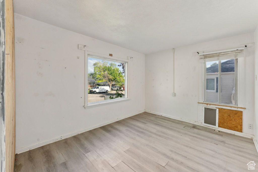 Unfurnished room with light wood-type flooring, healthy amount of natural light, and baseboards