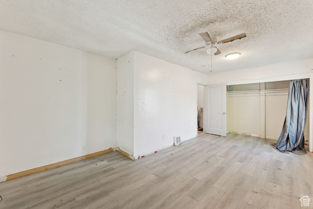 Unfurnished bedroom featuring light wood finished floors, baseboards, a textured ceiling, a closet, and a ceiling fan