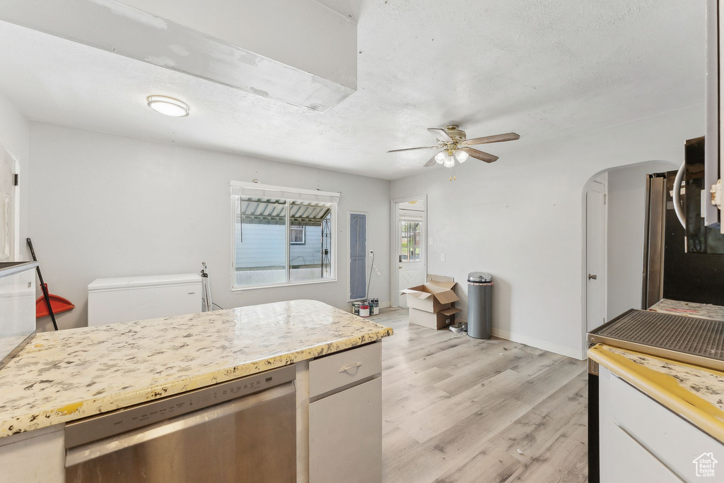 Kitchen featuring dishwasher, ceiling fan, light wood finished floors, light countertops, and baseboards