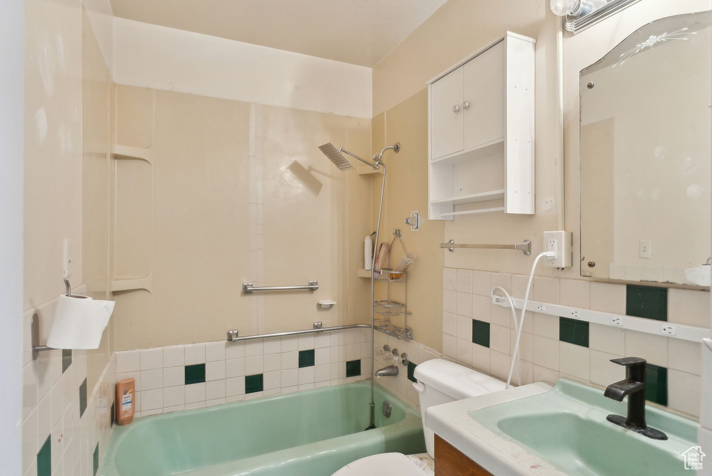 Bathroom with tile walls, toilet, decorative backsplash, shower / tub combination, and vanity