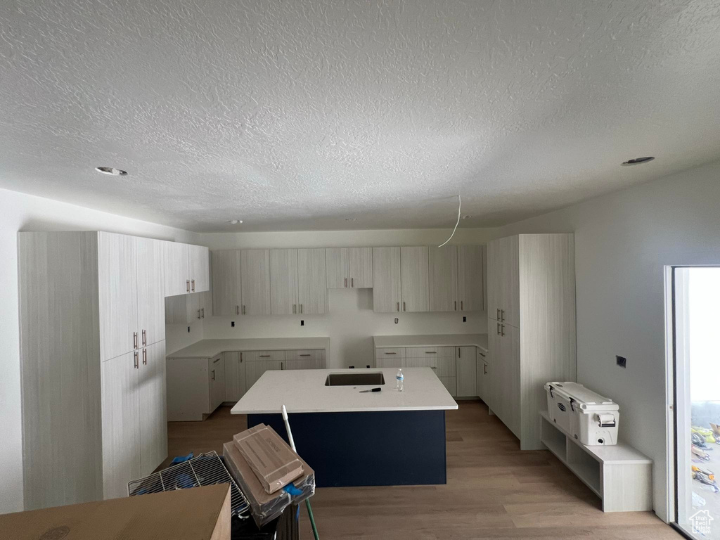 Kitchen featuring a center island, a textured ceiling, and light wood-style floors