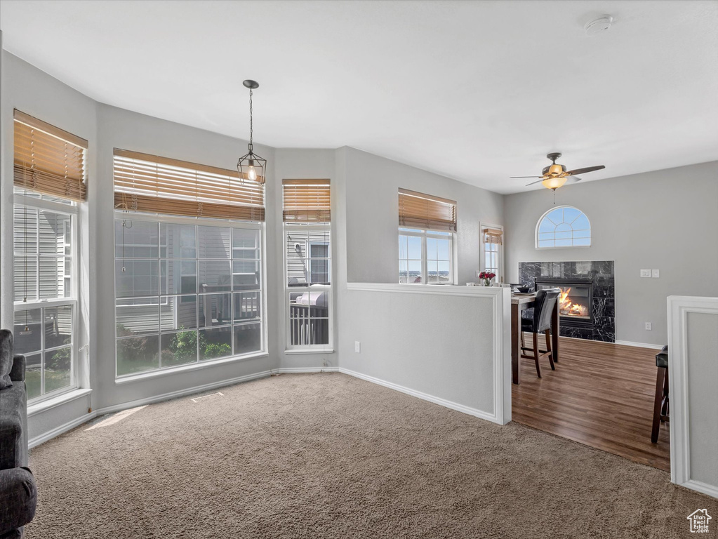 Living room with a ceiling fan, carpet floors, baseboards, and a fireplace