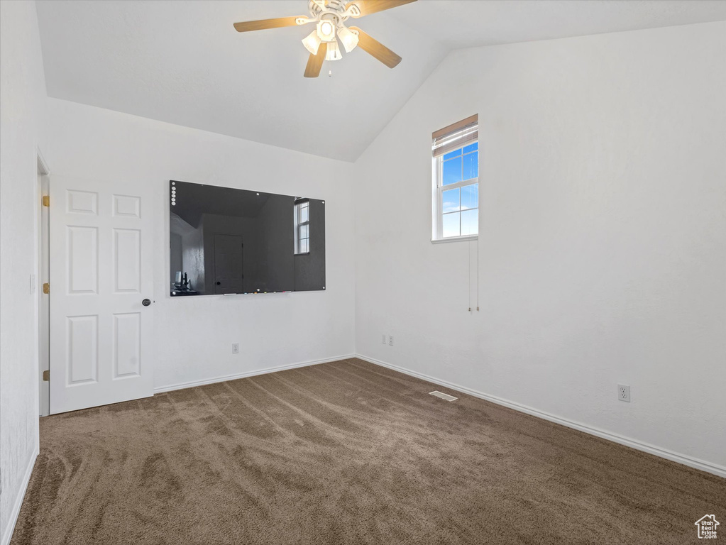 Unfurnished room featuring ceiling fan, carpet floors, vaulted ceiling, and baseboards