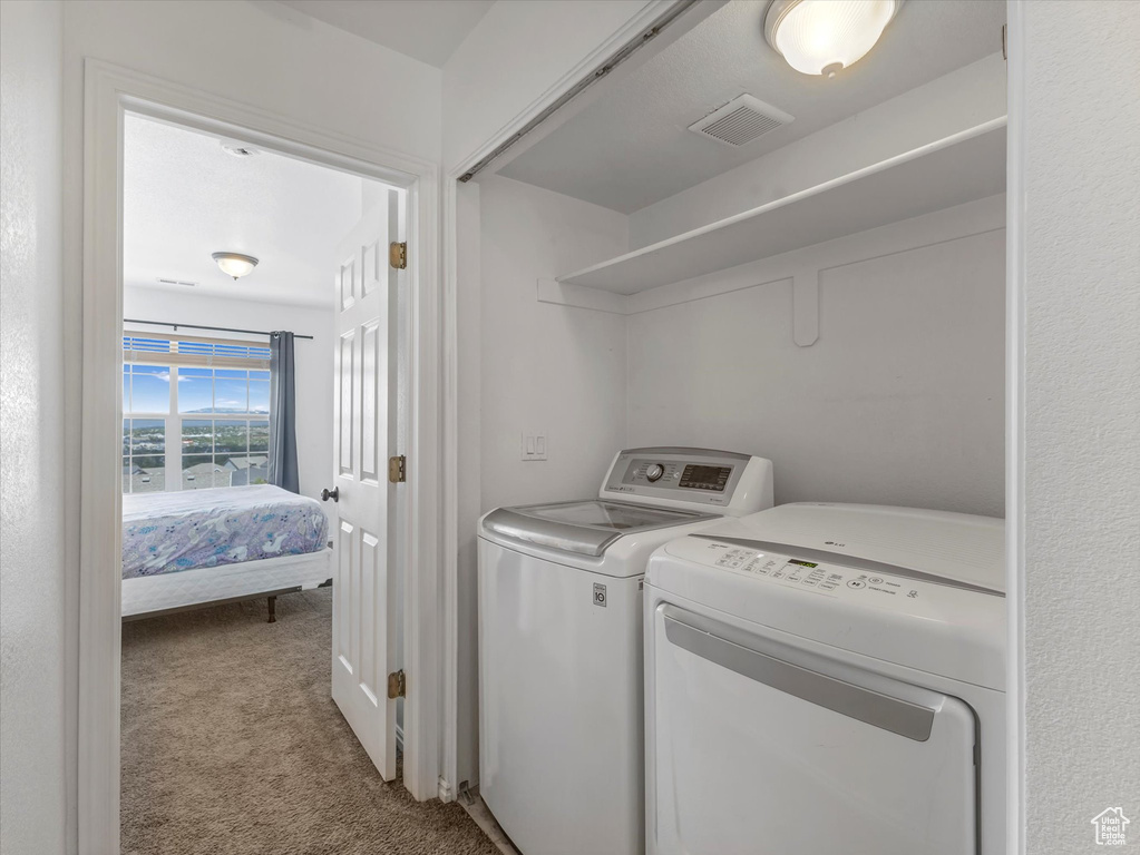 Laundry area featuring washer and clothes dryer and carpet flooring